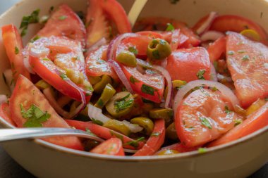 Kâsede taze ve basit bir domates salatası. Bitkilerle sulu kırmızı domateslerin yakın plan görüntüsü. Hafif ve sağlıklı mevsimlik yemekler için mükemmel..