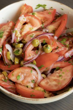 Kâsede taze ve basit bir domates salatası. Bitkilerle sulu kırmızı domateslerin yakın plan görüntüsü. Hafif ve sağlıklı mevsimlik yemekler için mükemmel..