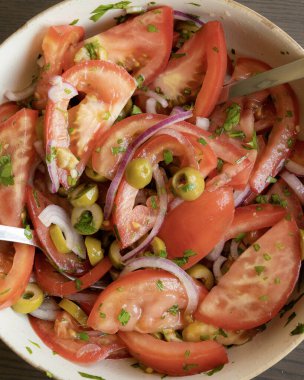 Kâsede taze ve basit bir domates salatası. Bitkilerle sulu kırmızı domateslerin yakın plan görüntüsü. Hafif ve sağlıklı mevsimlik yemekler için mükemmel..