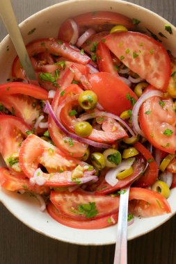 Kâsede taze ve basit bir domates salatası. Bitkilerle sulu kırmızı domateslerin yakın plan görüntüsü. Hafif ve sağlıklı mevsimlik yemekler için mükemmel..