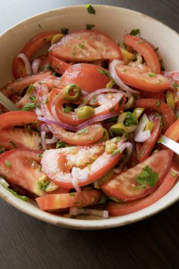 Kâsede taze ve basit bir domates salatası. Bitkilerle sulu kırmızı domateslerin yakın plan görüntüsü. Hafif ve sağlıklı mevsimlik yemekler için mükemmel..
