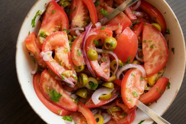Kâsede taze ve basit bir domates salatası. Bitkilerle sulu kırmızı domateslerin yakın plan görüntüsü. Hafif ve sağlıklı mevsimlik yemekler için mükemmel..