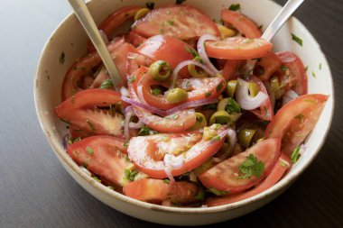 Kâsede taze ve basit bir domates salatası. Bitkilerle sulu kırmızı domateslerin yakın plan görüntüsü. Hafif ve sağlıklı mevsimlik yemekler için mükemmel..