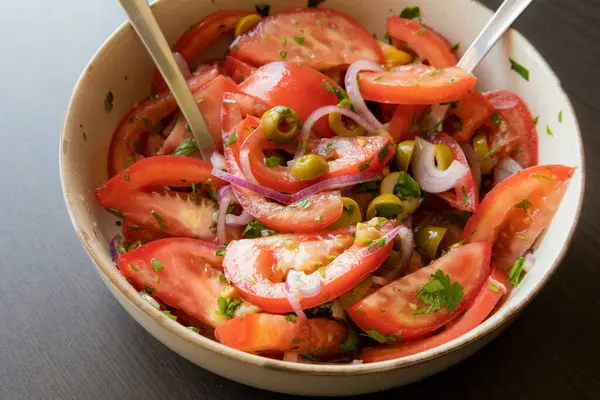 Kâsede taze ve basit bir domates salatası. Bitkilerle sulu kırmızı domateslerin yakın plan görüntüsü. Hafif ve sağlıklı mevsimlik yemekler için mükemmel..