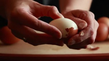 Kadın elleri haşlanmış yumurtayı kabuğundan çıkarıyor.