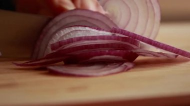 Mor soğanı ince ince dilimlere ayıran kadın tahtayı yakın.