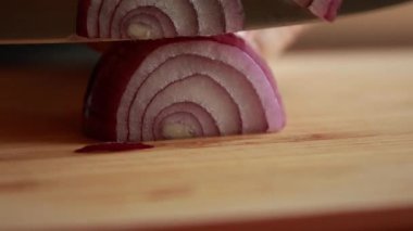 Mor soğanı ince ince dilimlere ayıran kadın tahtayı yakın.