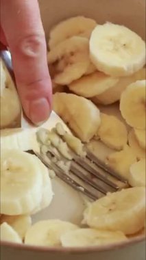 Muz dilimlerini çatalla kaseye koyup dikey olarak ezmek.