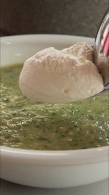 Beyaz kâsede sağlıklı yeşil bahar çorbası servis ediliyor. Dikey olarak.
