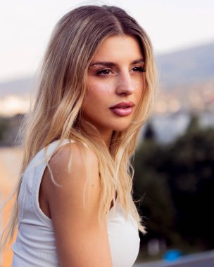  Güneş gören ateşli manken cilt parlamasını ve ışıltısını öptü ve festival makyajını yaptı. Gün batımından sonra çatıda çekilen cesur yaz titreşimleri ve şehir enerjisi.