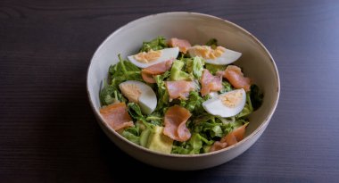Lezzetli ve sağlıklı salata, füme somon, haşlanmış yumurta, yeşillikler ve taze sebzeler. Protein açısından zengin ve temiz yemek, diyet ya da sağlıklı yaşam tarzı temaları için mükemmel.