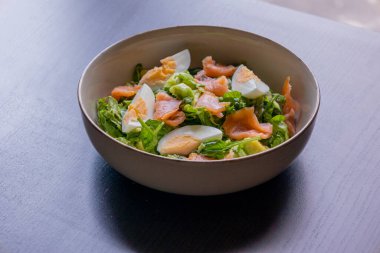 Lezzetli ve sağlıklı salata, füme somon, haşlanmış yumurta, yeşillikler ve taze sebzeler. Protein açısından zengin ve temiz yemek, diyet ya da sağlıklı yaşam tarzı temaları için mükemmel.