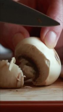 Tahta kesme tahtasıyla taze mantar kesen kadınların ellerini kapatın.