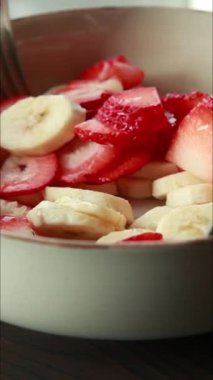 Bir kasede taze muz ve çilek dilimleriyle çatalları birbirine karıştırıyorum.