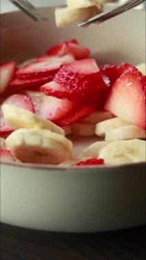 Bir kasede taze muz ve çilek dilimleriyle çatalları birbirine karıştırıyorum.