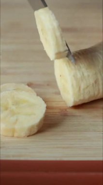 Tahta kesme tahtasında muz dilimleme dikey videoyu kapat