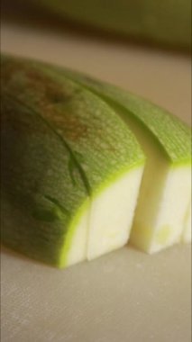 Mutfak ışığı altında beyaz kesme tahtasının üzerine kabak dilimliyorum.