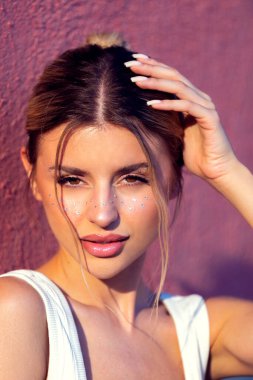 Pembe pullu, kalın makyajlı bir kadın. Güneş ışığına yakalanmış. Sanatsal ve şenlikli görünüş, festival, güzellik, moda veya yaz temalı hisse içeriği için mükemmel