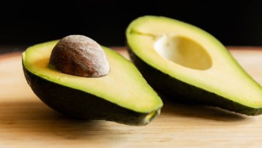 Tahtadaki dilimlenmiş avokado. Arka plan koyu renk. Yakın plan.