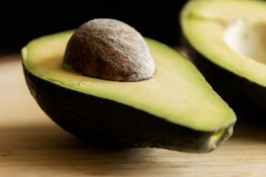 Tahtadaki dilimlenmiş avokado. Arka plan koyu renk. Yakın plan.