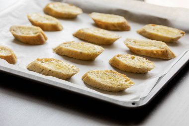  Bir tepside düzgünce dizilmiş ekmek dilimleri, crostini içinde pişirilmeye hazır.