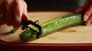  Tahta bir yüzeye salatalık soyan kadın elleri videosu.