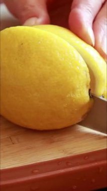Tahta üzerinde taze limon dilimleme dikey videoyu kapat