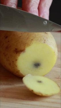  Çiğ patates dilimleri tahta bir kesme tahtasına serilmişti. Besin hazırlığının doğal dokusunu ve basitliğini yakalar.