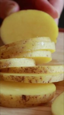  Çiğ patates dilimleri tahta bir kesme tahtasına serilmişti. Besin hazırlığının doğal dokusunu ve basitliğini yakalar.