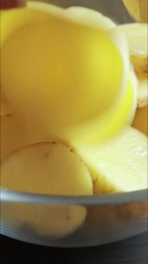  Çiğ patates dilimleri tahta bir kesme tahtasına serilmişti. Besin hazırlığının doğal dokusunu ve basitliğini yakalar.