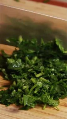 Kadın maydanozu tahta kesme tahtasıyla kesiyor. Dikey videoyu kapat.