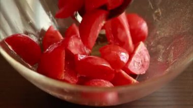 Terbiye edilip karıştırılan cam bir kasede doğranmış vişneli domateslerin yakın plan videosu.