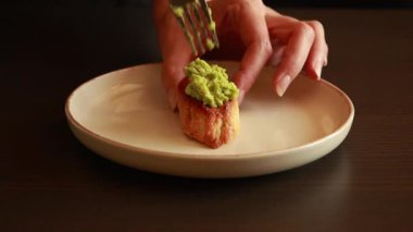  Kremalı avokado ve kızarmış vişneli domatesle kaplanmış crostini, zarif bir parti yemeği olarak servis ediliyor.