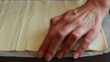 Düz bir yüzey üzerinde hamur hamuru kesen bir kadının yakın plan videosu.