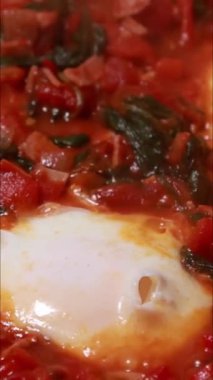 Shakshuka tarifi için pişirilen yumurta ve domateslerin dikey görüntüleri