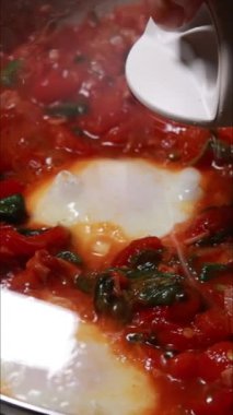 Shakshuka tarifi için pişirilen yumurta ve domateslerin dikey görüntüleri
