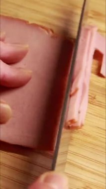 Kadın elleri kesme tahtasının üzerinde jambon hazırlıyor ve doğruyor.