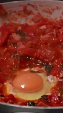Shakshuka tarifi için pişirilen yumurta ve domateslerin dikey görüntüleri