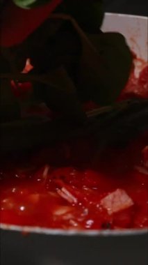 Domates ve ıspanak sotelenmesinin dikey videosu.