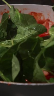 Domates ve ıspanak sotelenmesinin dikey videosu.