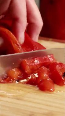 Kadın elleri kırmızı dolmalık biber dilimleyip dikey mutfak videosu hazırlıyor.