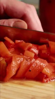 Kadın elleri kırmızı dolmalık biber dilimleyip dikey mutfak videosu hazırlıyor.