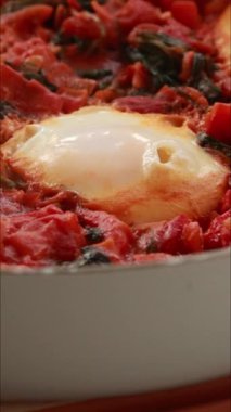 Yumurta ve domatesli geleneksel shakshuka dikey çekim pişiriyor.