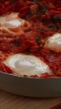 Yumurta ve domatesli geleneksel shakshuka dikey çekim pişiriyor.