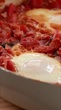 Yumurta ve domatesli geleneksel shakshuka dikey çekim pişiriyor.