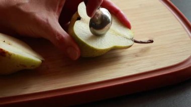 Kadınların elleri tahta kesme tahtasındaki taze armudu kesiyor.