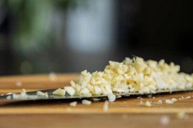 Mutfak bıçağında yeni doğranmış sarımsağın yakın plan fotoğrafı.