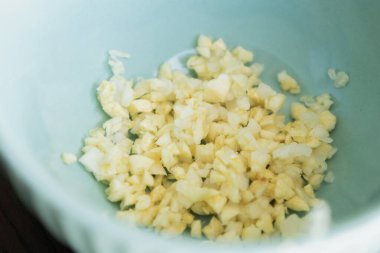 Küçük mavi kasede doğranmış sarımsak. Yaklaş.