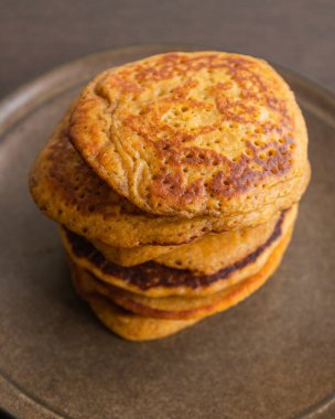 Üzerinde şurup olan kabak kabaklı krep yığınının yakın plan fotoğrafı.