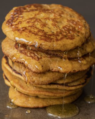 Üzerinde şurup olan kabak kabaklı krep yığınının yakın plan fotoğrafı.